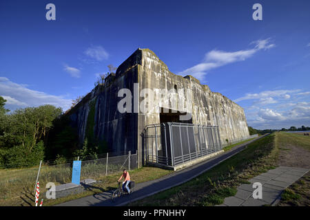 Cyclists in front of the Weser-facing side of the submarine bunker Valentin, taken on 11.08.2018. The submarine bunker Valentin in Bremen-Farge was built on a surface of more than 3.5 hectares in the years 1943 to 1945 by forced laborers, making it the largest freestanding bunker in Germany. In this important armament project of the German Navy naval submarines of type XXI were to be manufactured in section construction. After the World War, the Federal Navy used parts of the site as a material store until 2010, and in the years 2011 to 2015, a visitor center with the memorial site Denkort Bun Stock Photo