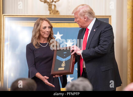Valerie Nessel, widow of Technical Sergeant John A. Chapman, United States Air Force, left, stands with US President Donald J. Trump, center, as she accepts the Medal of Honor posthumously from the President during a ceremony in the East Room of the White House in Washington, DC on Wednesday, August 22, 2018. Sergeant Chapman is being honored for his actions on March 4, 2002, on Takur Ghar mountain in Afghanistan where he gave his life to save his teammates. Credit: Ron Sachs/CNP /MediaPunch Stock Photo