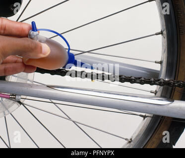 Man dripping lubricating oil onto bicycle chain Stock Photo