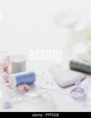Cotton reels, tailors chalk, pins and beads scattered on a white surface Stock Photo