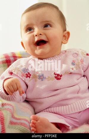 Seven month old baby girl sitting, smiling, mouth open Stock Photo