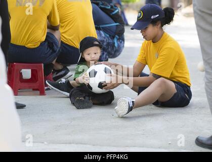 TRANG, Vietnam (May 24, 2018) A Sailor currently deployed in support of Pacific Partnership 2018 (PP18), plays with a young child at Khanh Hoa Social Protection Center during a community event. PP18's mission is to work collectively with host and partner nations to enhance regional interoperability and disaster response capabilities, increase stability and security in the region, and foster new and enduring friendships across the Indo-Pacific Region. Pacific Partnership, now in its 13th iteration, is the largest annual multinational humanitarian assistance and disaster relief preparedness miss Stock Photo