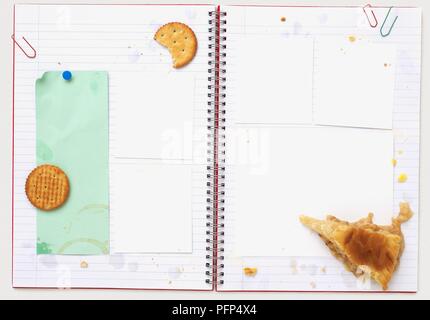 Open spiral notebook with cheese crackers, pie and grease marks Stock Photo