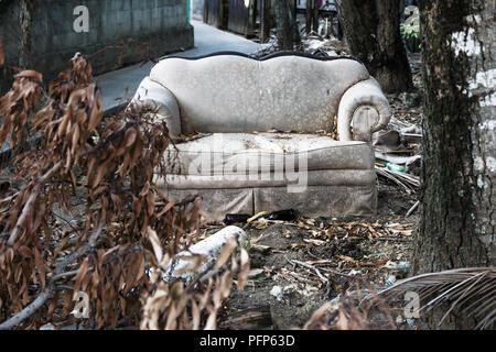 Abadoned couch with trash in dry garden in Utila, Honduras, Central America Stock Photo