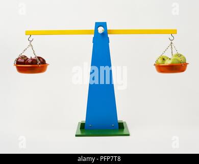 Red and green apples on toy scales Stock Photo