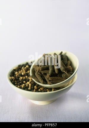 Bowl of peppers with bowl of catkin-like pepper fruits on top, close-up Stock Photo