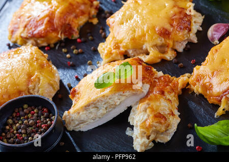 Pork Chops Topped with finely chopped Onions, Mayo and melted Cheese on a black slate plate on a wooden table, view from above, close-up Stock Photo