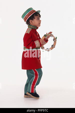 Boy in marching band uniform playing tambourine, side view Stock Photo