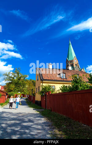 Old Swedish house and red fence with the Sofia Church in the background in Vitabergsparken, Sodermalm, Stockholm, Sweden Stock Photo