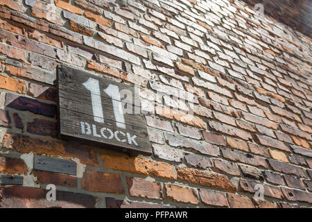 Wooden sign for block 11 on a brick wall in the former Nazi concentration camp Auschwitz, Poland Stock Photo