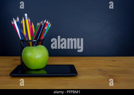Back to school background with tablet, pencils and  green apple over chalkboard Stock Photo