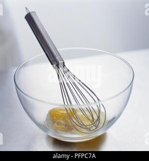Egg yolks, mustard and vinegar in glass mixing bowl with wire whisk, close-up Stock Photo