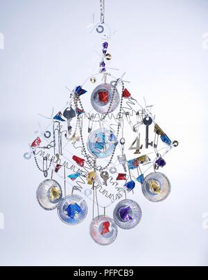 Wire coat hangers and shiny objects, including paper clips, safety pins and old keys, as decoration suspended from a hook Stock Photo