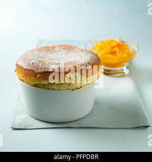 Grand marnier souffle in serving dish and sliced oranges in glass bowl on blue napkin Stock Photo