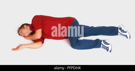 Young man lying on side in the recovery position Stock Photo