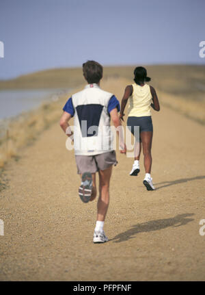 Man and woman jogging along shore of a lake Stock Photo