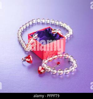 Strand of glass beads, heart-shaped ring, and a gift box Stock Photo