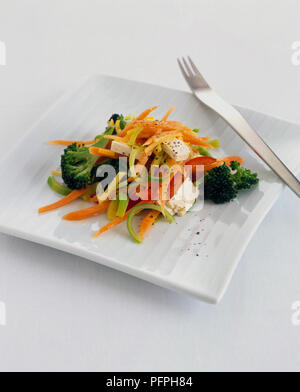 Broccoli, bell peppers, carrot and feta cheese salad on square white plate with fork Stock Photo