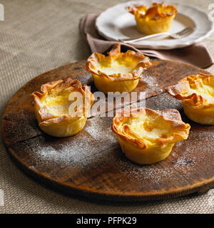 Cardamom custard filo tartlets dusted with icing sugar, on wooden board Stock Photo