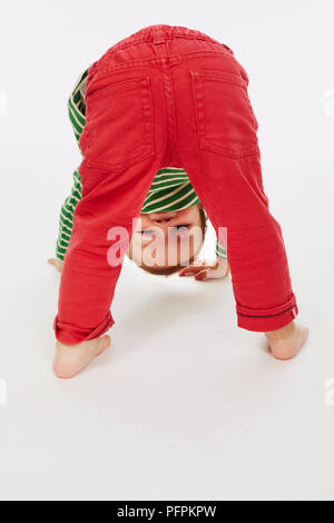 Little boy in green stripey top bending over (Model age - 22 months) Stock Photo