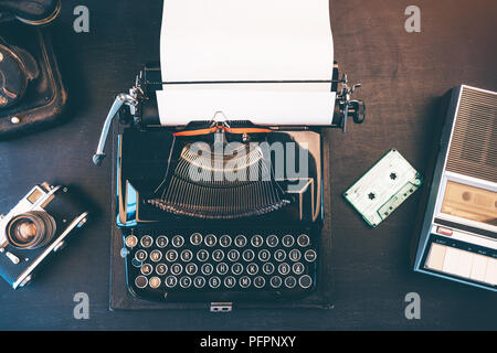 Top view of vintage journalist workspace with telephone, typewriter and audio cassette tape player Stock Photo