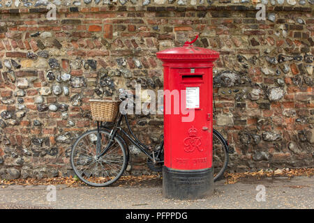 English post box and bicycle against an ancient stone and brick wall. Stock Photo