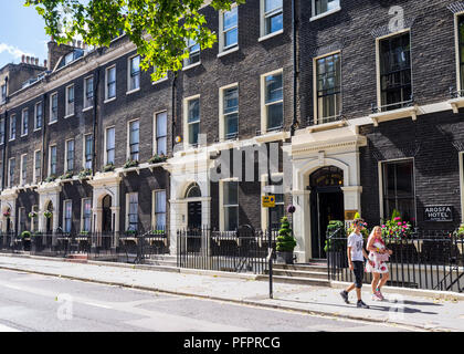 Couple walking in Gower Street in front of classic Georgian style townhouses in a summer sunny day. Fitzrovia, London, UK Stock Photo