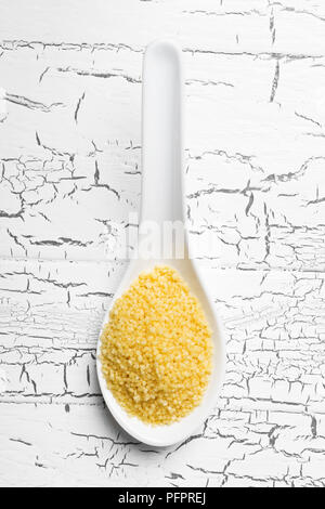 Heap of raw, uncooked couscous in white on white wooden table background from above Stock Photo
