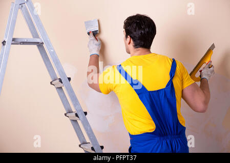 Young contractor employee applying plaster on wall Stock Photo