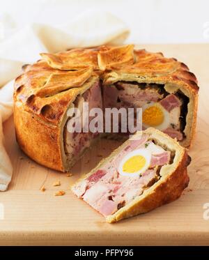 Cold chicken pie with boiled egg at centre, single slice cut away Stock Photo