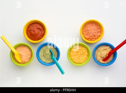 Homemade meat, vegetable, cheese and fruit purees in brightly coloured bowls with spoons Stock Photo