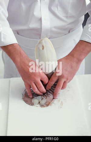 Removing bone of cuttlefish, pressing down to release internal shell and peeling back outer skin Stock Photo