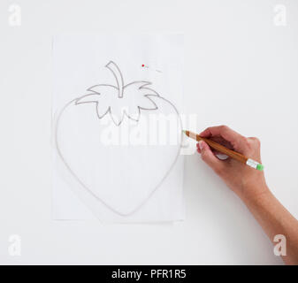 Man using pencil to draw strawberry on tracing paper, close-up Stock Photo