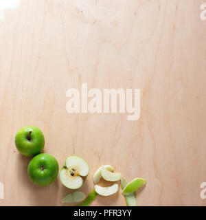 Whole apples and sliced and peeled segments on wooden surface Stock Photo