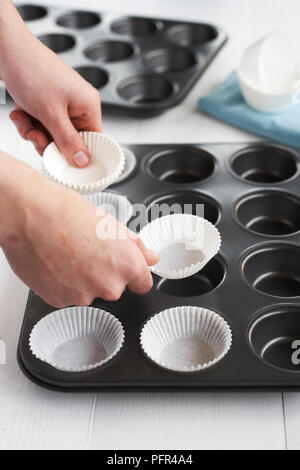 Placing cupcake cases in muffin tray Stock Photo