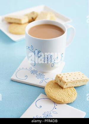 Cup of milky tea, butter biscuits and shortbread, Dot decorated cup and coaster Stock Photo