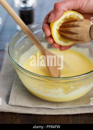 Adding freshly squeezed lemon juice to hollandaise sauce Stock Photo