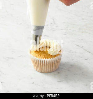 Piping butter icing on top of cupcake Stock Photo
