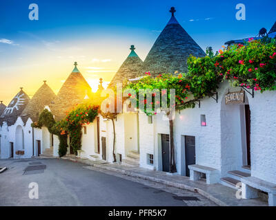 Traditional Trulli houses in Alberobello village, illuminated by sunrise. Apulia region - Italy. Stock Photo