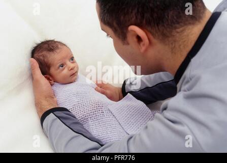 Man wrapping baby boy in blanket, close-up Stock Photo