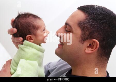 Man holding a small baby close to his face, side view Stock Photo
