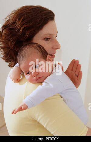 Woman holding baby against shoulder while patting her back Stock Photo