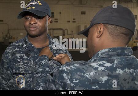 NORFOLK, Va. (May 24, 2018) -- Personnel Specialist 2nd Class Igbekele Oki, from Nigeria, assigned to USS Gerald R. Ford's (CVN 78) administration department, receives his enlisted surface warfare specialist pin from Chief Personnel Specialist Jerry Eunice during an awards ceremony in the ship's hangar bay. Stock Photo