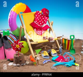 Child's bucket and spade, flippers, deckchair and various other seaside holiday items on beach Stock Photo