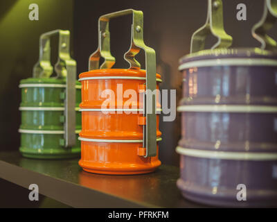 Orange, Purple and green tiffin carrier. Colorful vintage food carrier on wooden shelf. Stock Photo