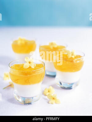 Orange, lemon and young coconut jelly (Woon ma praw orn), served in glasses, decorated with jasmine flowers Stock Photo