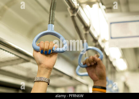 Woman with blue color nail hand holding a handle on train  Stock Photo