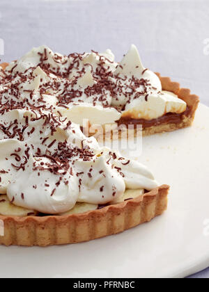 Banoffee pie with slice removed served on white plate, close-up Stock Photo