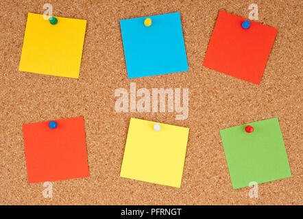 Colourful pieces of paper pinned to a cork pin board Stock Photo