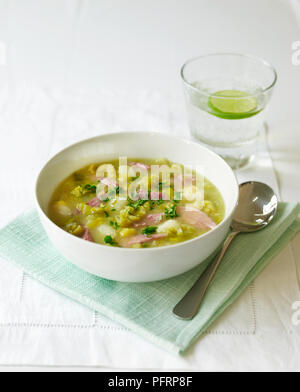 Bowl of pea and ham soup, spoon, and a glass of water Stock Photo